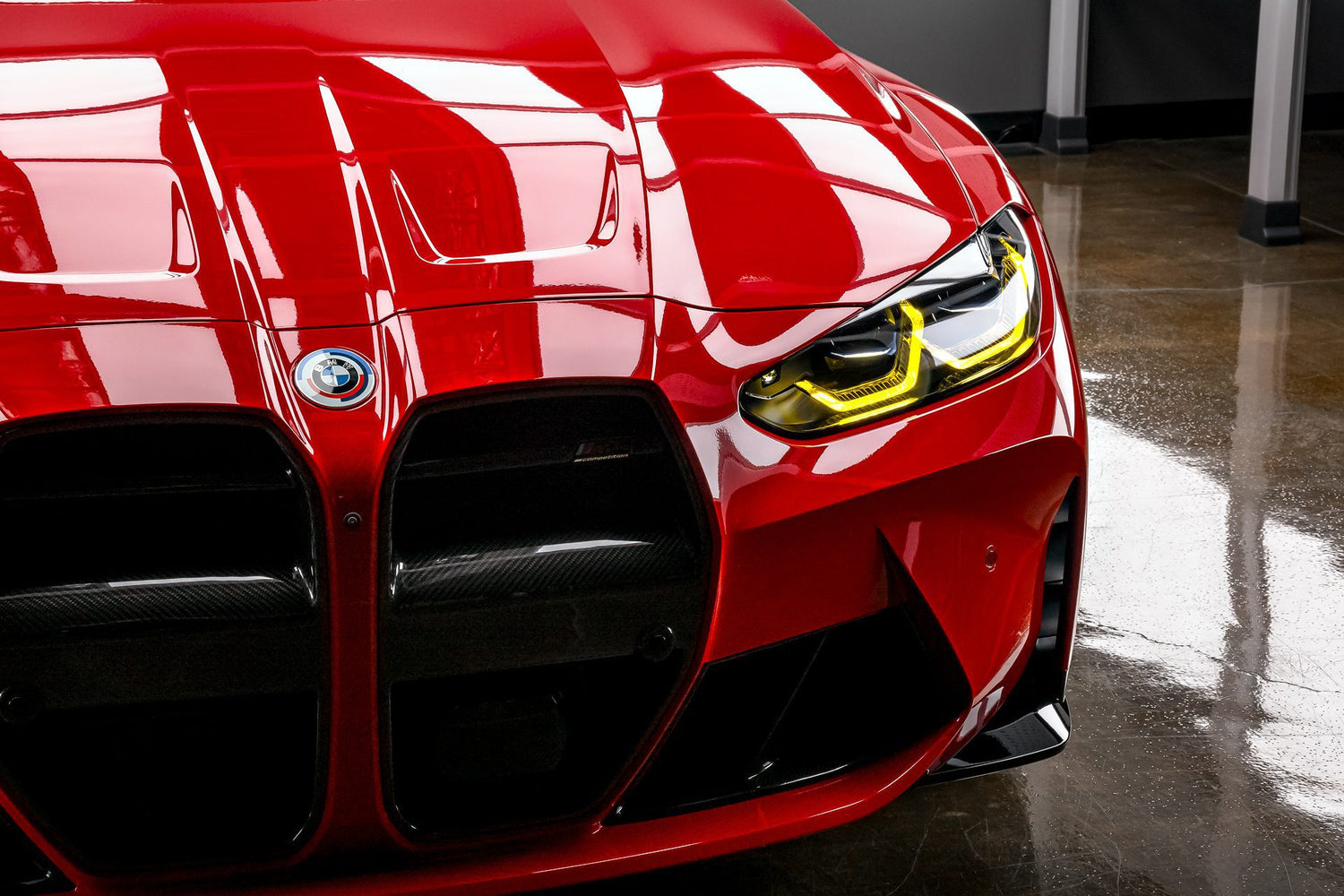 A close-up of the front of a vibrant red BMW M3, showcasing the exceptional shine achieved through professional car detailing near me in Sydney, New South Wales, Australia. The glossy paint, clean lines of the grill, and detailed headlight demonstrate the high-quality results of expert car detailing services. If you're looking for meticulous detailing near me to enhance the brilliance of your BMW, this image exemplifies the potential outcome.